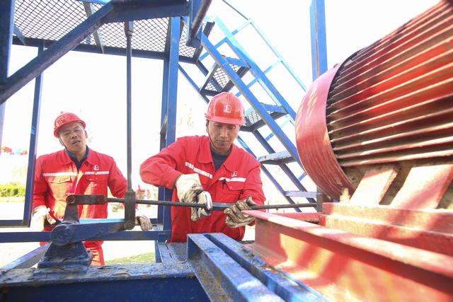 图2：集团公司技能大师景天豪（左）和厂主任技师葛红雨调整古泌125井抽油机远程自动刹车装置，提高生产效率。.JPG