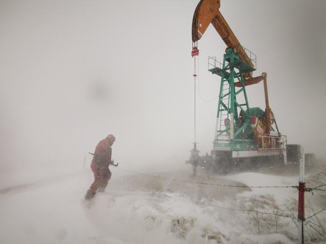 图为员工顶风冒雪巡检油井。.jpg