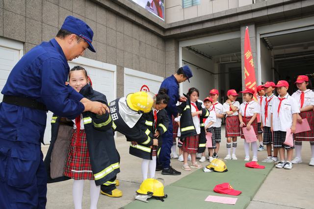 图四、消防员协助同学们试穿消防服，体验小小消防员。.JPG